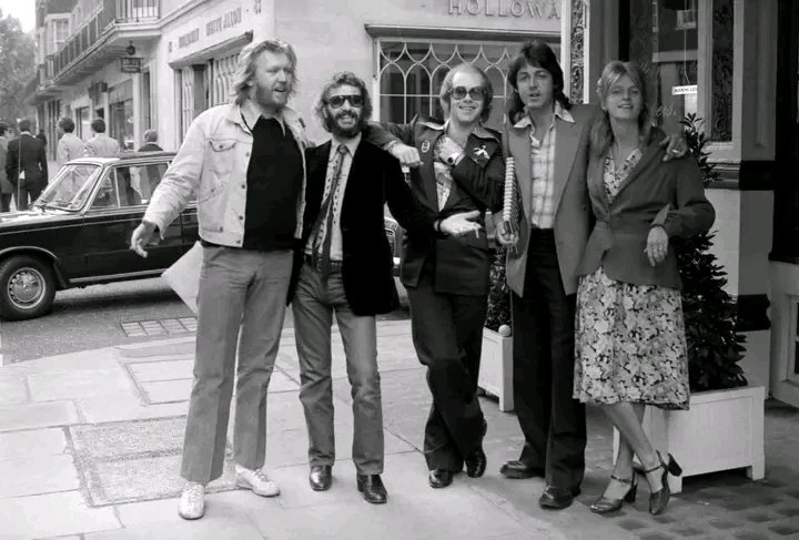 HARRY NILSSON, RINGO STARR, ELTON JOHN, PAUL McCARTNEY, LINDA McCARTNEY and JOE ENGLISH outside a restaurant in Mayfair, London. 1975. Photos taken by TERRY O’NEILL.